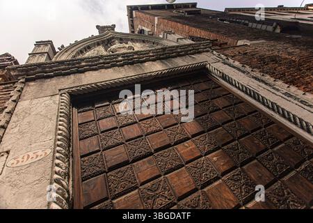 Venedig, Italien 1. Januar 2025: Aufwändige Schnitzereien zieren eine verwitterte Holztür und verleihen einem historischen venezianischen Gebäude in italien Charakter Stockfoto