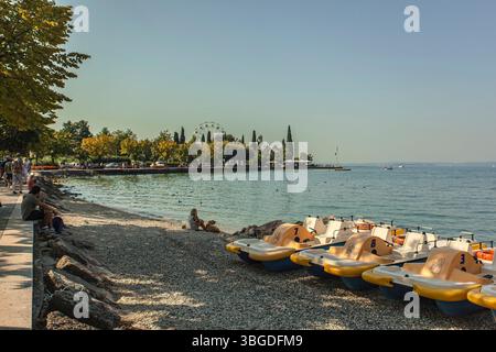 Gardasee, Italien 3. Januar 2025: Tretboote am Ufer des gardasees, mit Touristen, die den sonnigen Tag genießen Stockfoto