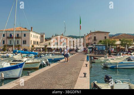 Gardasee, Italien 3. Januar 2025: Touristen wandern am sonnigen Sommertag im Hafen von bardolino, gardasee, italien Stockfoto