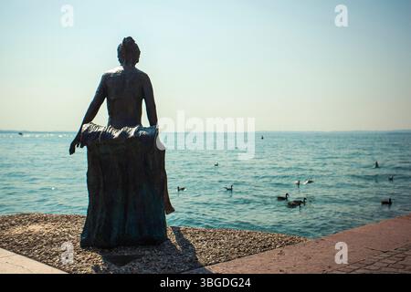 Gardasee, Italien 3. Januar 2025: Bronzestatue mit Blick auf den gardasee mit schwimmenden Enten in bardolino, italien Stockfoto
