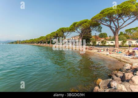 Gardasee, Italien 3. Januar 2025: Touristen, die am Strand des gardasees in der Nähe von bardolino und lazise, italien, baden und schwimmen Stockfoto