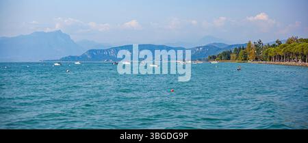 Gardasee, Italien 3. Januar 2025: Malerischer Blick auf den gardasee mit Motorbooten und Bergen im Hintergrund, in der Nähe von bardolino und lazise, italien Stockfoto