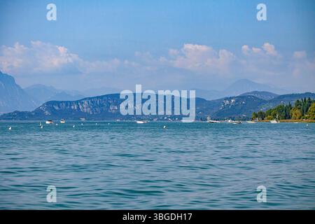 Gardasee, Italien 3. Januar 2025: Malerischer Blick auf den gardasee mit Motorbooten und Bergen im Hintergrund, in der Nähe von bardolino und lazise, italien Stockfoto
