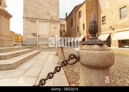 Modena, Italien 1. Januar 2025: Rostreiche Kette, die an kleinen Steinsäulen hängt, die den ghirlandina-Turm auf der piazza grande in modena schützen Stockfoto