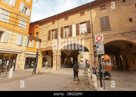 Modena, Italien 1. Januar 2025: Touristenwanderung in einer malerischen Straße mit Bögen und bunten Gebäuden im Stadtzentrum von modena, italien Stockfoto