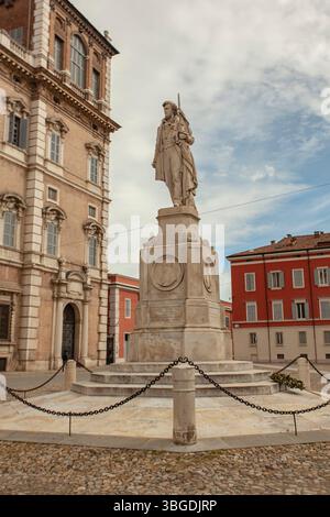 Modena, Italien 1. Januar 2025: Steinstatue des ciro menotti, italienischer Patriot, mit einer Flagge auf der piazza roma, modena, mit herzoglichem Palast im Hintergrund Stockfoto