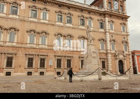 Modena, Italien 1. Januar 2025: Frau, die mit einem Hund auf der piazza roma vor dem herzoglichen Palast und dem Denkmal für ciro menotti in modena, italien Stockfoto