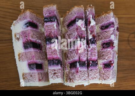 Ein Stück Kuchen mit Heidelbeeren und weißem Zuckerguss. Der Kuchen wird in sechs Stücke geschnitten Stockfoto