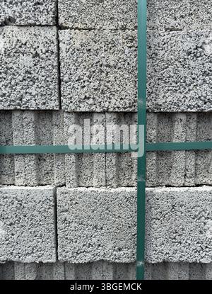 Stapel aus Porenbetonblöcken mit rauer Oberflächenstruktur, gesichert durch grüne Bänder, vertikale Ausrichtung. Ideal für Bau- und Industrieanwendungen Stockfoto