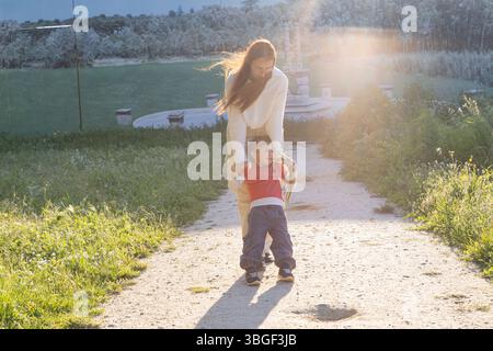 Mutter schwingt ihren Sohn in einem Park während Sonnenuntergang Stockfoto