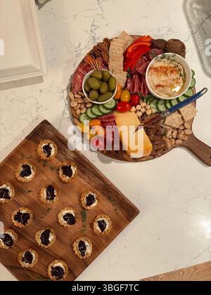 Blick von oben auf eine Wurstplatte mit Wurstwaren, Käse, Oliven, Nüssen und Vorspeisen auf einer Marmoroberfläche. Stockfoto