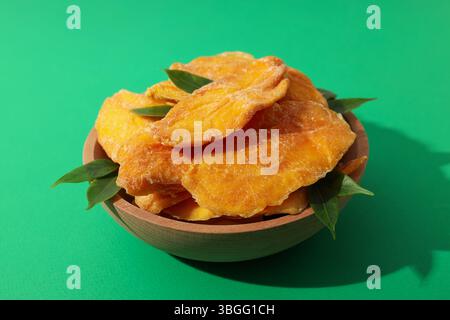 Getrocknete Mangochips in einer Schüssel auf grünem Hintergrund Stockfoto