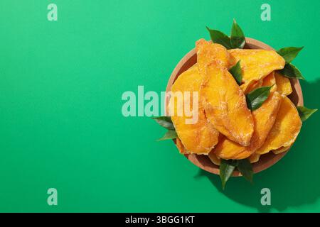 Getrocknete Mangochips in einer Schüssel auf grünem Hintergrund Stockfoto