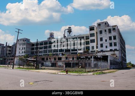 Das verlassene Packard Werk in Detroit, Michigan, steht im Verfall mit zersplitterten Fenstern, Graffitis und Industrieruinen unter einem blauen Himmel. Stockfoto