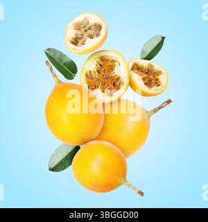 Köstliche reife Passionsfrüchte mit grünen Blättern, die auf hellblauem Hintergrund fallen Stockfoto
