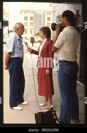 Carol Luper, ein Fernsehreporter für WBNS 10TV, wird gezeigt, wie er einen nicht identifizierten Mann vor den Büros der Stadt Columbus in der 50 West Gay Street interviewt. Das 1980 aufgenommene Foto zeigt die Szene auf der Gay Street mit einem Kameraoperator von Channel 10, der das Interview aufnimmt. Stockfoto