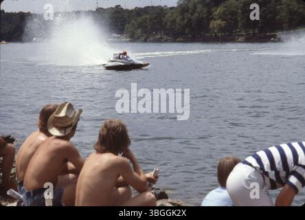 Während der Buckeye Cup Regatta fährt ein blaues Wasserflugzeug entlang des Scioto River, das von drei jungen Männern am Ufer beobachtet wird. Die Buckeye Cup Regatta ist ein jährlich stattfindendes Bootsrennen auf dem Scioto River oberhalb des Griggs Dam. Stockfoto