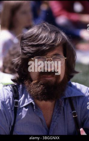 Ein nicht identifizierter Mann mit braunen Haaren, Bart und Schnurrbart schaut direkt in die Kamera. Sein Auge ist teilweise offen und fängt seinen ehrlichen Ausdruck ein. Stockfoto