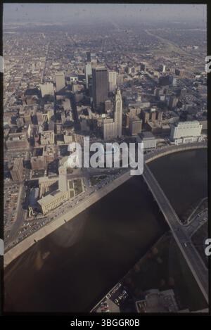 Ein Blick aus der Vogelperspektive von ca. 1977 nach Osten über den Scioto River in Richtung Innenstadt von Columbus. Die Broad Street Bridge überspannt den Fluss. Zu den bemerkenswerten Gebäuden gehören das Federal Building, die Columbus Central Police Station, das Rathaus, das Verkehrsministerium und der Leveque Tower. Stockfoto