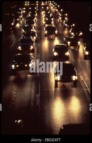 Ein nächtlicher Blick auf einen nicht identifizierten Abschnitt der Autobahn. Das Bild erfasst die beleuchtete Straße, Straßenlaternen und den allgemeinen Verkehrsfluss in der Gegend. Stockfoto
