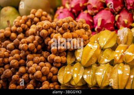 Ein Haufen asiatischer Früchte in den Regalen, darunter Bananen, Mangos und Sternenfrüchte Stockfoto