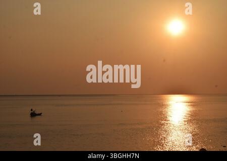 Die goldene Stunde auf dem Meghna River zeichnet ein ruhiges Bild von Fischern, die den Rhythmus der Natur umarmen. Stockfoto