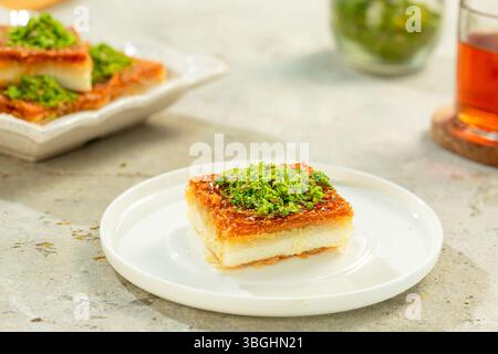 Knafeh, osmanisches arabisches Dessert aus dem Nahen Osten, serviert mit Käse oder Sahne und Pistazienstreuseln. Stockfoto