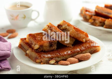 Namoura, arabisches Dessert aus dem Nahen Osten, gefüllt mit Mandeln und Zimt, mit Ghee, weißem Hintergrund. Stockfoto