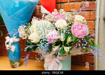 Wunderschöner Blumenstrauß mit pastellfarbenen Rosen, rosa Pfingstrosen, Babyatmen und verschiedenen Blüten, ideal für Hochzeiten, Geschenke oder Dekoration. Stockfoto