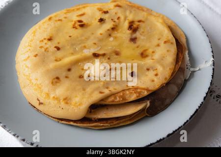 Stapel hausgemachter Pancakes mit geschmolzener Butter auf rustikalem Teller Stockfoto