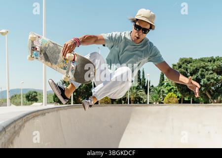Junger Mann Skateboarden und einen Trick im Skatepark machen Stockfoto