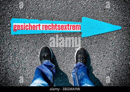 Beine, die vor einem Pfeil nach rechts mit der Inschrift gesicherter Rechtsextremist stehen, klassifiziert das Bundesamt für Verfassungsschutz die AfD als gesicherter Rechtsextremist, Fotomontage Stockfoto