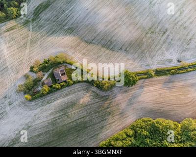 Aus der Vogelperspektive auf ein bewirtschaftetes Feld und ein verlassenes Bauernhaus in der ländlichen Landschaft des Cesane-Parks in der Nähe von Urbino, Marken, Mittelitalien Stockfoto