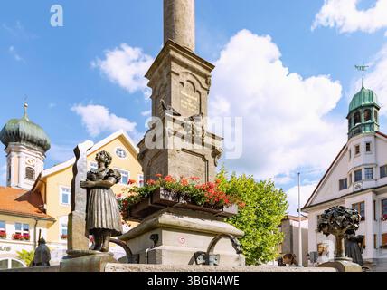 Brunnen mit Bronzestuppe des Strumpfehemaligen und Mariensäule am Marienplatz mit Pfarrkirche St. Nikolaus und Rathaus in Immenstadt im Allgäu in Bayern Stockfoto