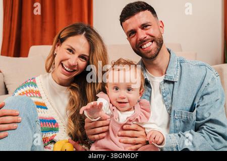 Ein herzerwärmendes Porträt, das eine glückliche Familie zeigt, die wertvolle Momente mit ihrem liebenswerten Baby genießt und Freude und Liebe ausstrahlt, während sie ein entzückendes miteinander teilt Stockfoto