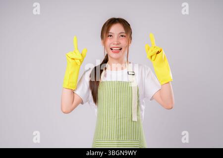 Der Job einer Frau, die eine gelbe Schürze und Handschuhe trägt, zeigt. Sie lächelt und ist glücklich Stockfoto