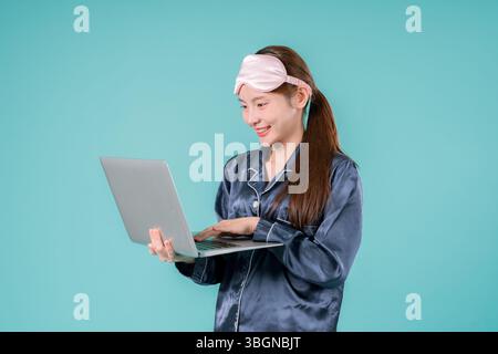 Asiatisch tragender Pyjama Unternehmer Notebook Social Lady, die online arbeitet, Eine junge Geschäftsfrau im lässigen Stil mit Laptop für Arbeit und Studium in einem Mod Stockfoto
