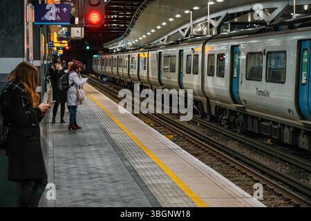 London, Vereinigtes Königreich - 02. Februar 2019: Passagiere warten am Bahnsteig am Bahnhof London Bridge, leere Bahngleise, Lichter leuchten in dunkler Nacht A Stockfoto