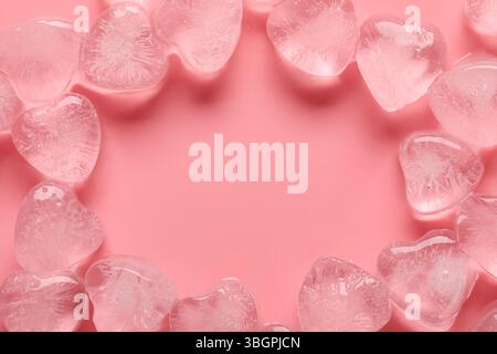 Rahmen aus herzförmigen Eiswürfeln auf rosa Hintergrund Stockfoto