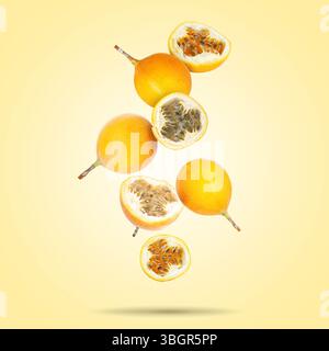 Köstliche reife Passionsfrüchte, die auf blassgelbem Farbverlauf fallen Stockfoto