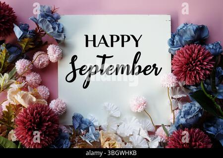 Frohe September-Text mit Blumendekorationen auf rosa Hintergrund Stockfoto