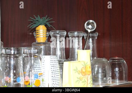 Ein ordentlich angeordnetes Küchenregal mit einer Sammlung von auf dem Kopf stehenden klaren Trinkgläsern. Es gibt verschiedene Arten von Gläsern im Regal. Stockfoto