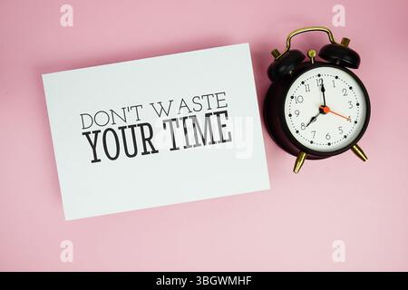 Verschwenden Sie nicht Ihre Zeit Text auf Papier Karte Draufsicht auf rosa Hintergrund Stockfoto