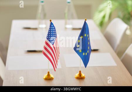 Flaggen der Vereinigten Staaten und der Europäischen Union stehen bei internationalen Verhandlungen an einem Tisch Stockfoto