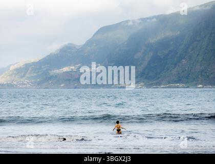 Reisebilder - Madeira SEIXAL, MADEIRA, PORTUGAL - 25. APRIL: Eine junge Frau schwimmt im Meer gesehen am 25. April 2025 in Seixal, Madeira, Portugal. ** Stockfoto