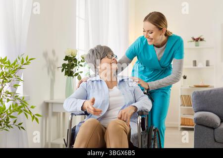 Eine professionelle Krankenschwester hilft und unterstützt eine behinderte alte Dame im Rollstuhl Stockfoto