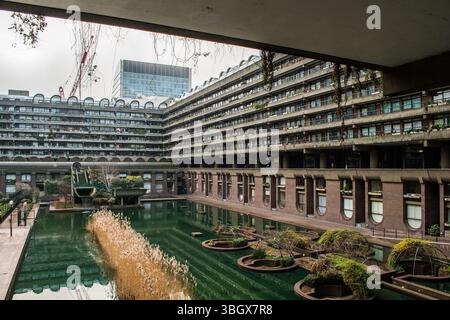 Barbican Estate in London mit Blick auf das barbikanische Wasser – brutalistische Architektur, Brunnen und städtisches Grün in einer kulturellen Umgebung. Stockfoto