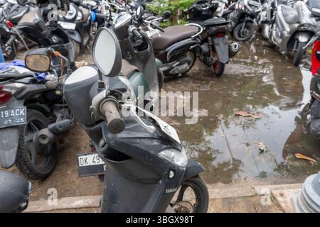 Bali, Indonesien - 17. Dezember 2024: Das schwarze Yamaha-Motorrad parkt auf vielen anderen Motorrädern. Das Motorrad ist durch Regen nass Stockfoto