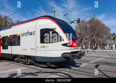 KONSTANZ, DEUTSCHLAND - 5. APRIL 2025: Ein moderner Zug in weiß und rot mit schlankem Design wird an einem Bahnübergang in Konstanz gesehen Stockfoto