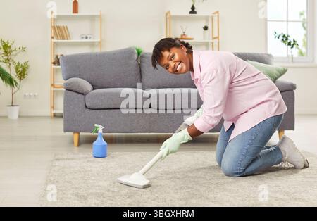 Porträt Einer glücklichen afroamerikanischen Frau, die zu Hause Teppiche saugt Stockfoto